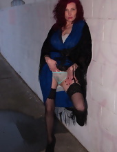 Mature flasher puts a hand in panties standing by a wall